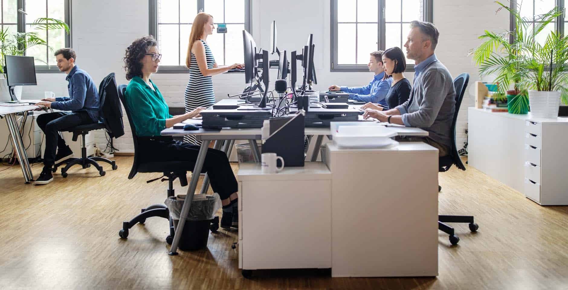 Flera personer sitter vid sina skrivbord i ett öppet kontorslandskap.