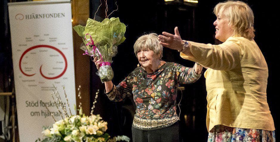 Dagny Carlsson står på en scen med mikrofon och håller i en blombukett.