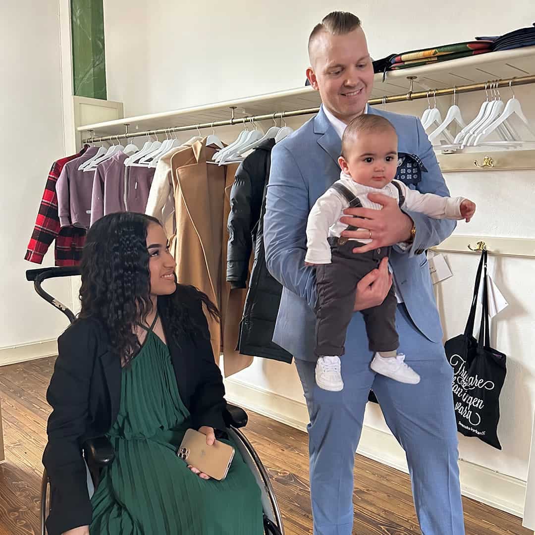 Carolina Hamnefjäll sitter i en rullstol med sin sambo som står bred vid med deras son i famnen.