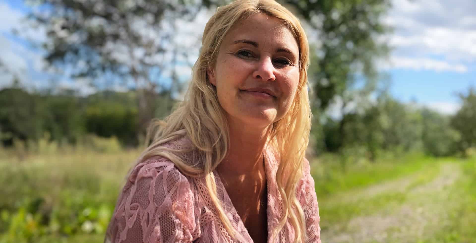 Bild på Johanna sittandes utomhus i solen.