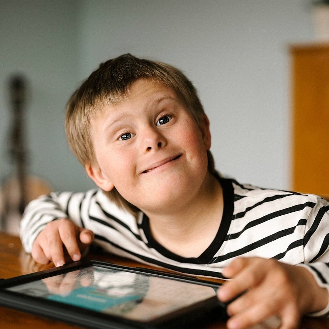 Ett bild på en pojke med Downs syndrome som sitter vid ett bord.