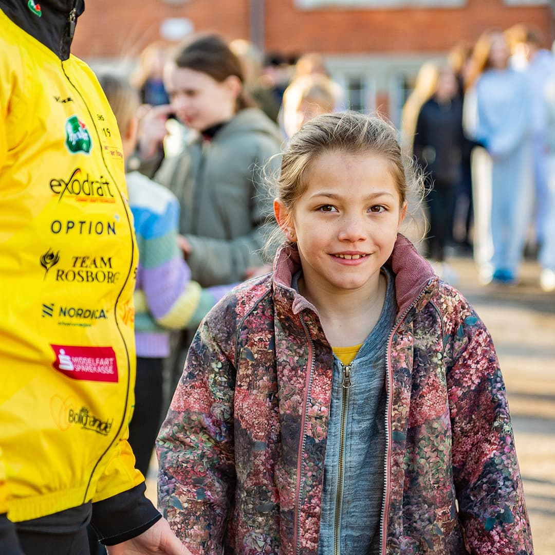 En flicka som står utomhus och kollar in i kameran