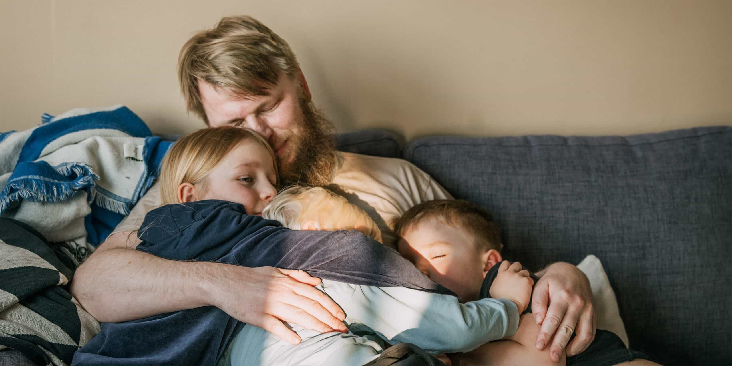 Torsten sitter med sina barn i soffan.