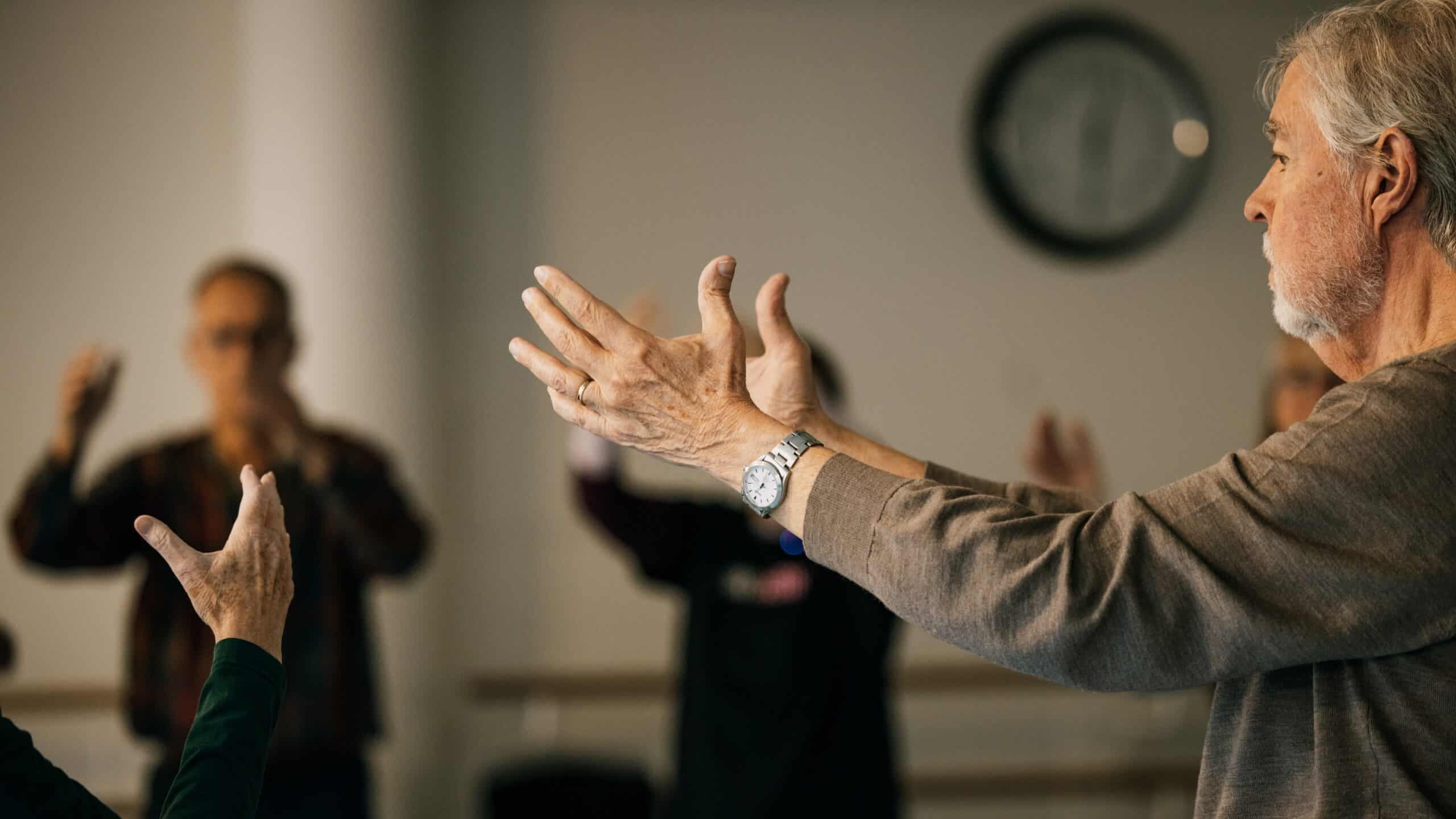 Närbild på händer som rör sig rytmiskt tillsammans med andra deltagare i bakgrunden.