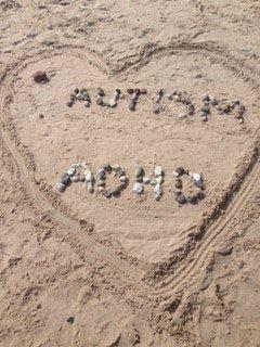 Ett hjärta ritat i sanden med stenar inuti som formar orden "Autism" och "ADHD."
