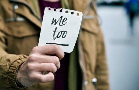 En person som håller upp en lapp med texten "Me too."
