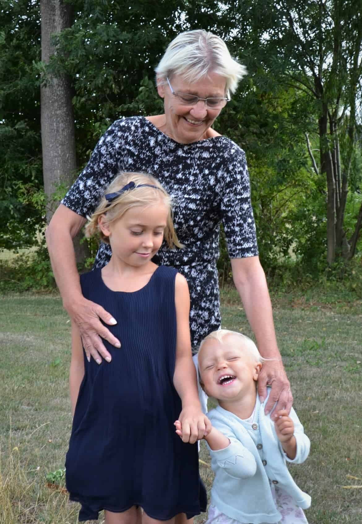 Emelys mamma står med sina barnbarn på gräset.