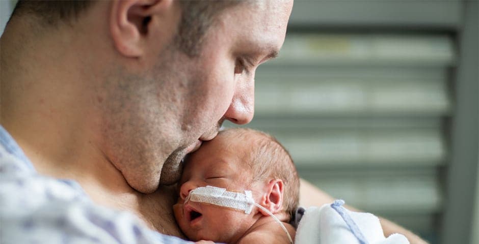 Far tar hand om sitt för tidigt födda barn att göra hud till hud på sjukhus