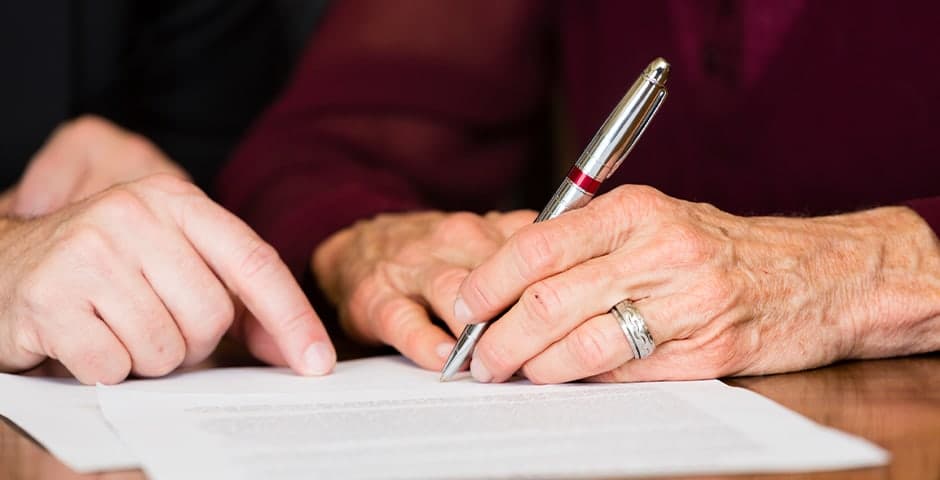 Äldre kvinna signerar sitt testamente
