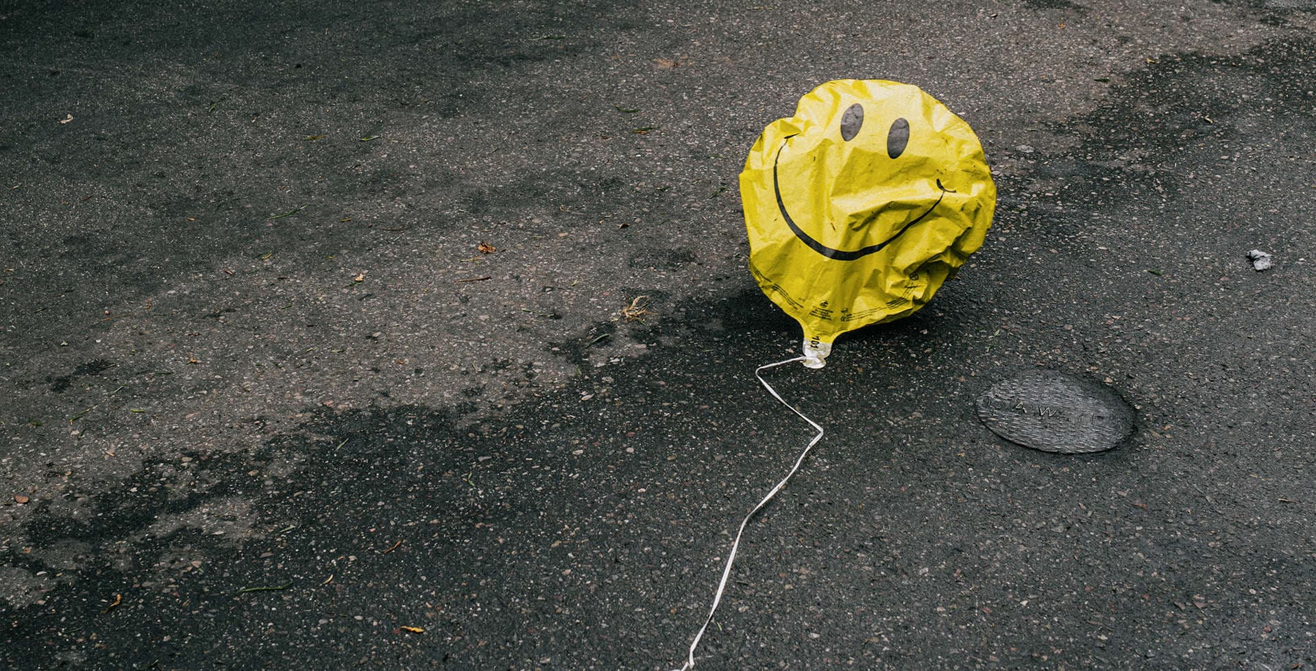 Foto på en gul ballong med en glad emoji-figur som ligger på marken