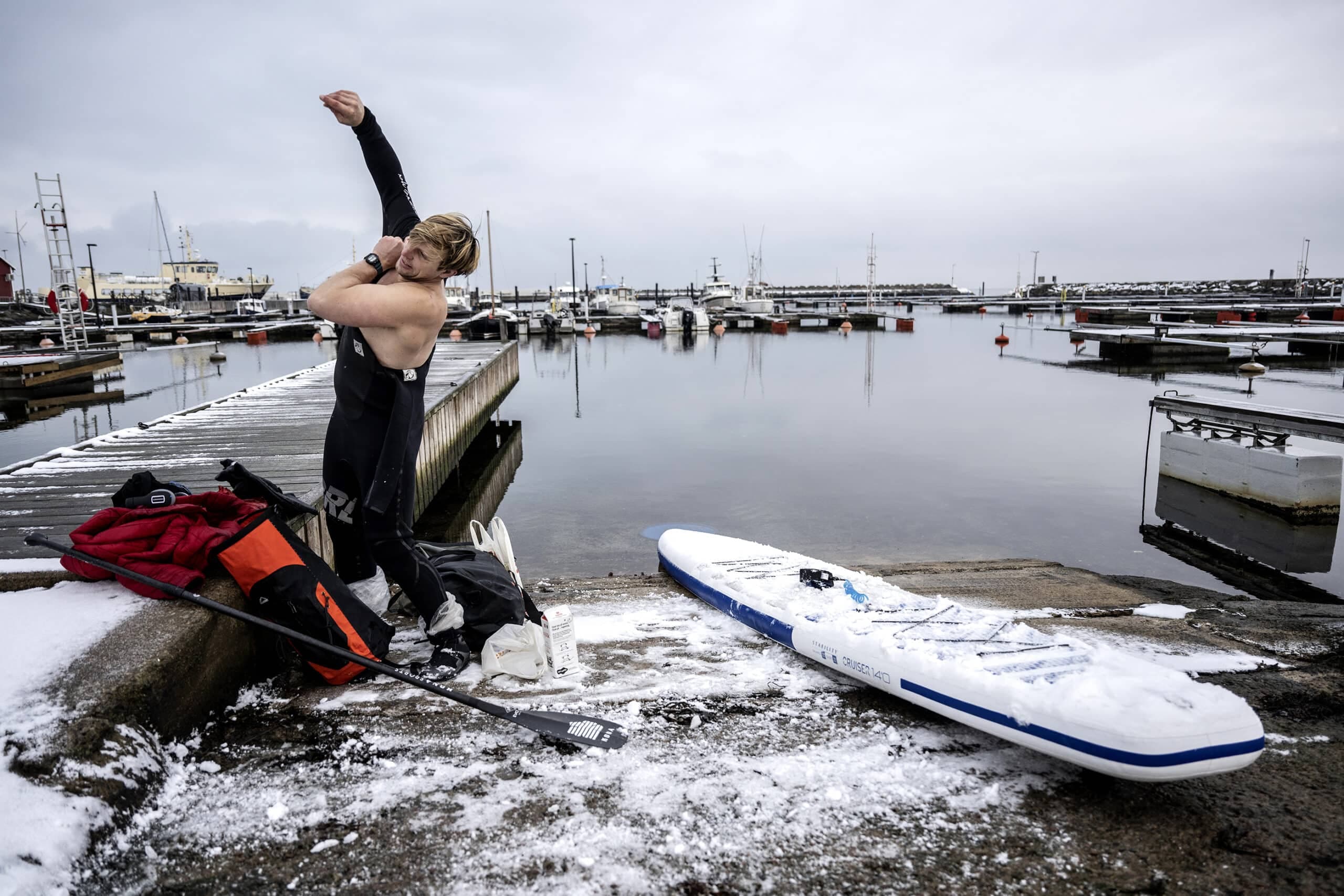 Bild på Jonas Böhlmark som sätter på sig sin torrdräkt nere vid vattnet. Fotograferat av Niklas Gustavsson.