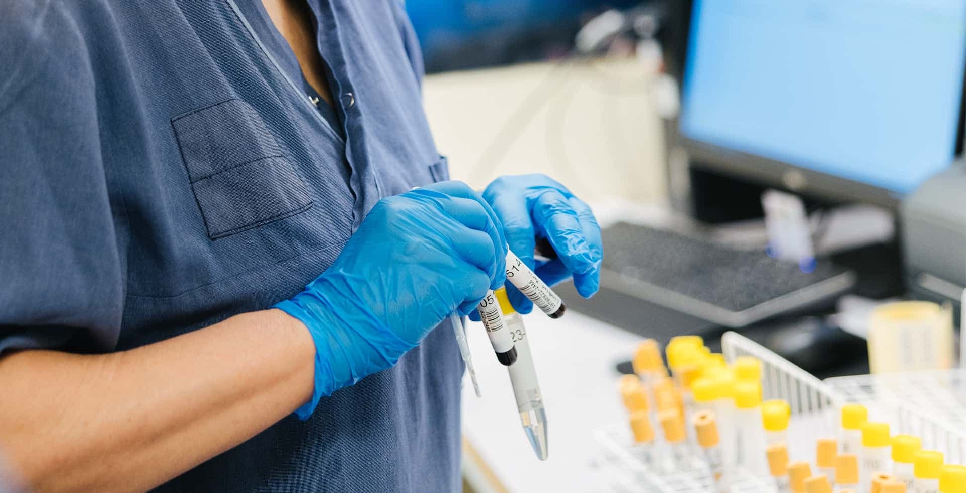 En närbild på en forskare med handskar som jobbar med prover.