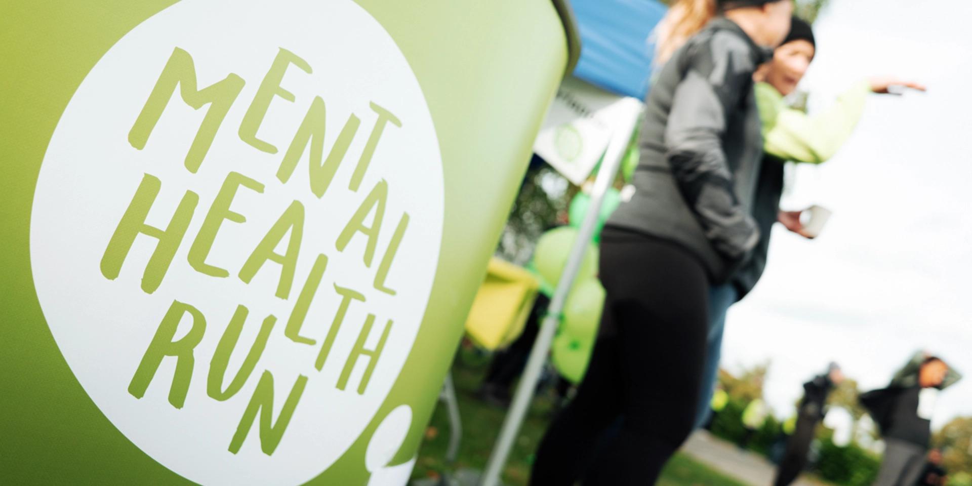 Bild på ett bord med Mental health runs logga med personer i bakgrunden.