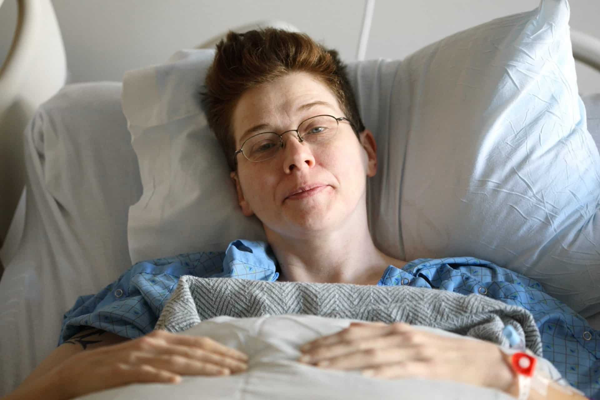En kvinna ligger i en sjuksäng på sjukhus