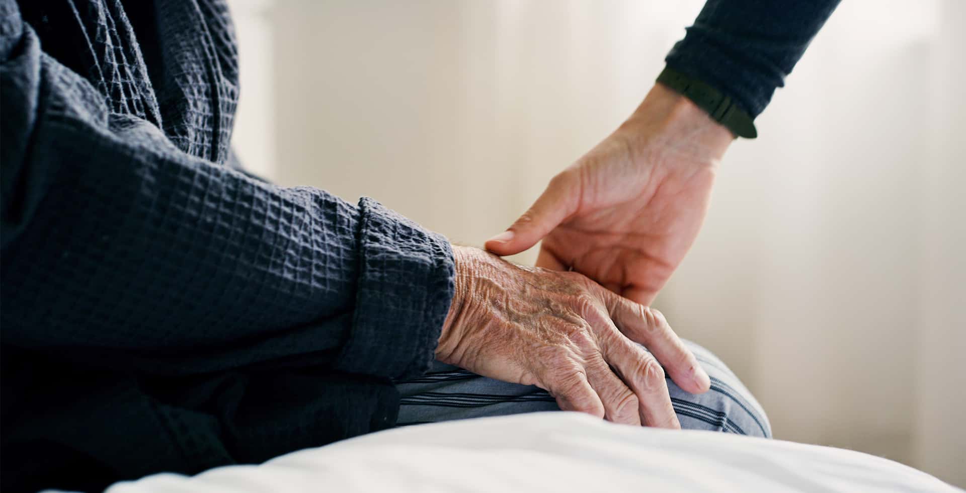 En person sträcker sin hand mot en äldre persons hand.