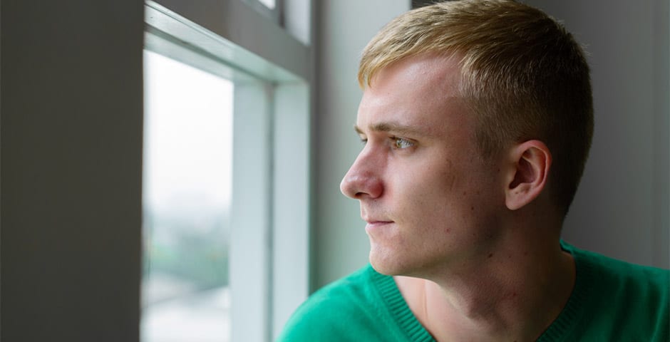 Deprimerad ung man tittar ut genom fönster