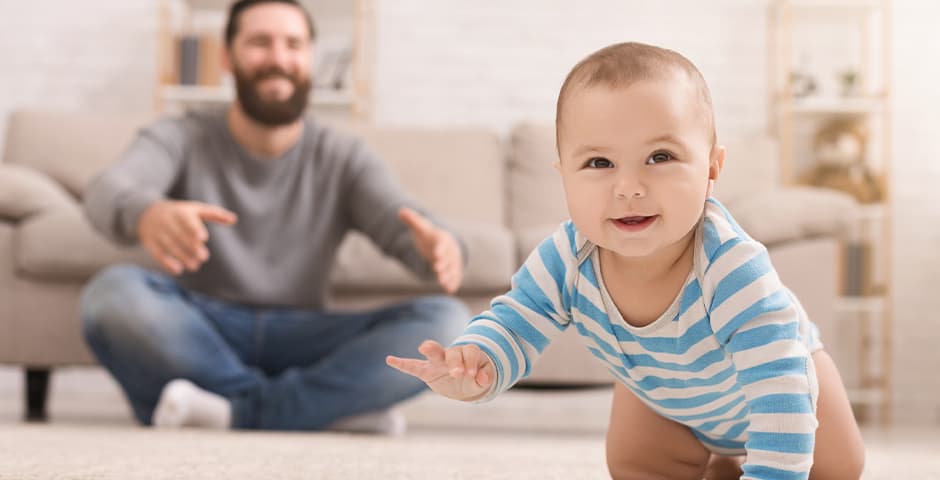 Glad bebis kryper på golvet med pappa