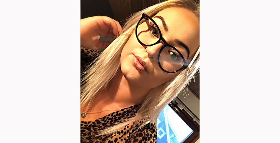 En ung kvinna med långt blont hår och glasögon har tagit en selfie.