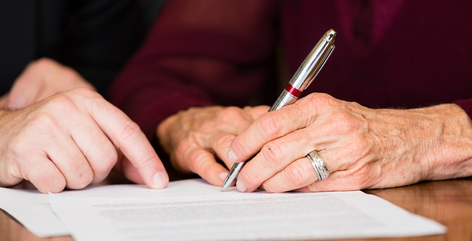 Äldre kvinna signerar sitt testamente