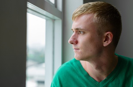 Ung kille tittar bedrövad ut genom fönstret