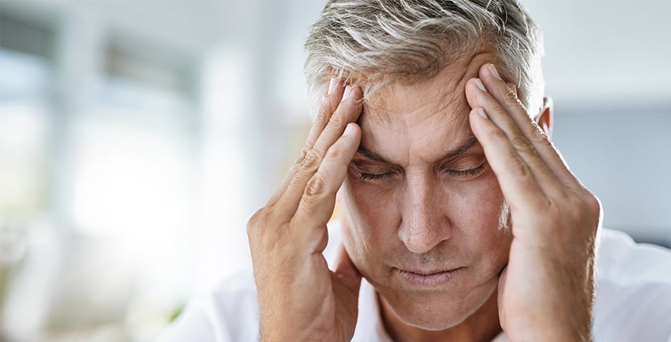 Medelålders man har huvudvärkoch håller sig om huvudetman har svår huvudvärk