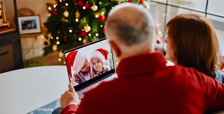 Äldre par talar med sitt barnbarn på datorn