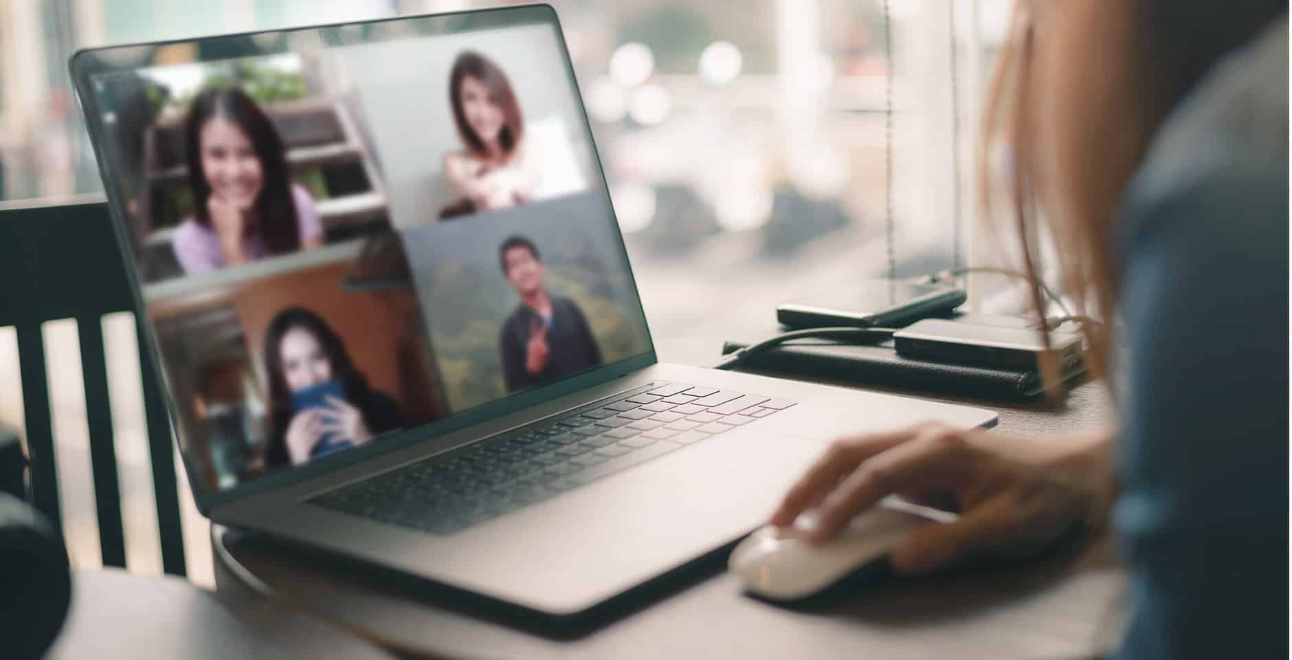 Kvinna sitter hemma och har ett digitalt möte med kollegor på en skärm
