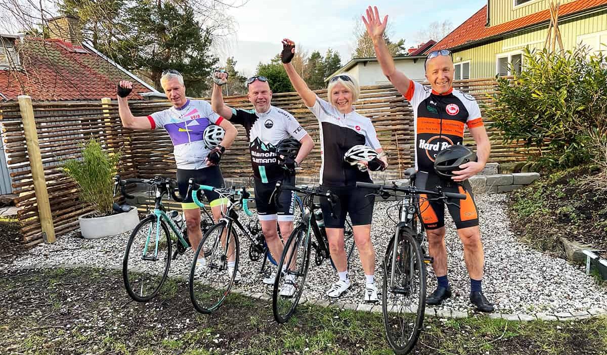 Fyra personer som poserar med sina cyklar, iklädda träningskläder.