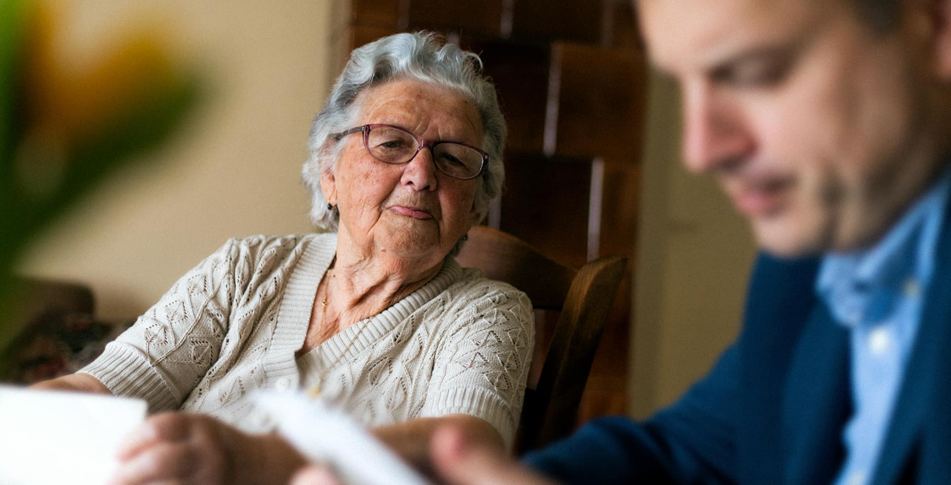 En nyfiken gammal pensionär sitter med en man som läser ett papper