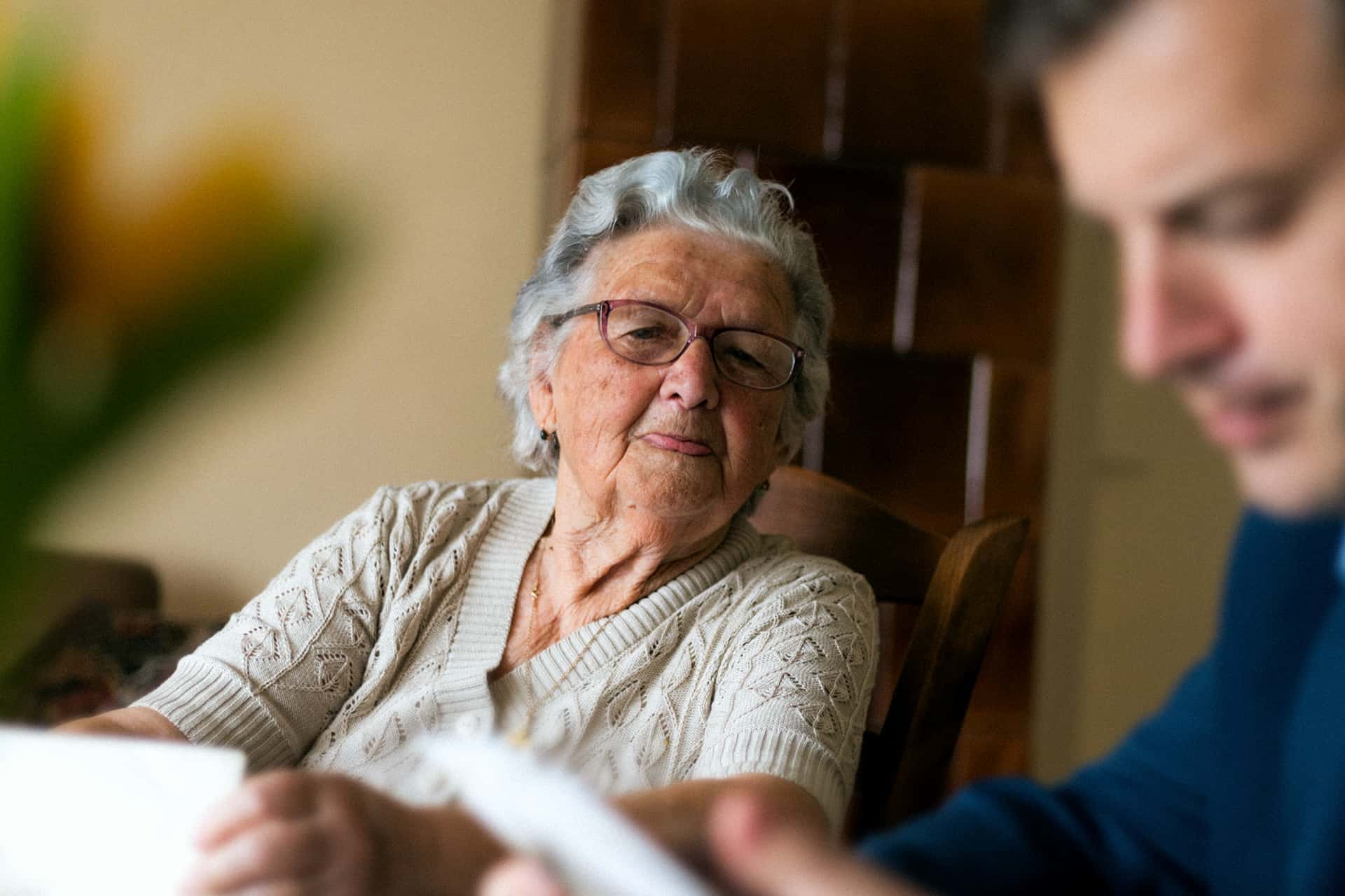 En nyfiken gammal pensionär sitter med en man som läser ett papper