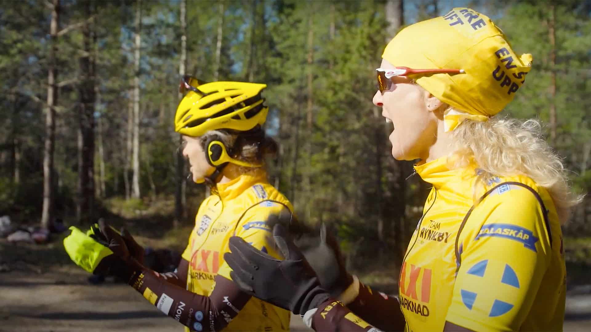 Två personer ifrån team Rynkeby står och hurrar på skolelever som springer skolloppet - barn springer för barn