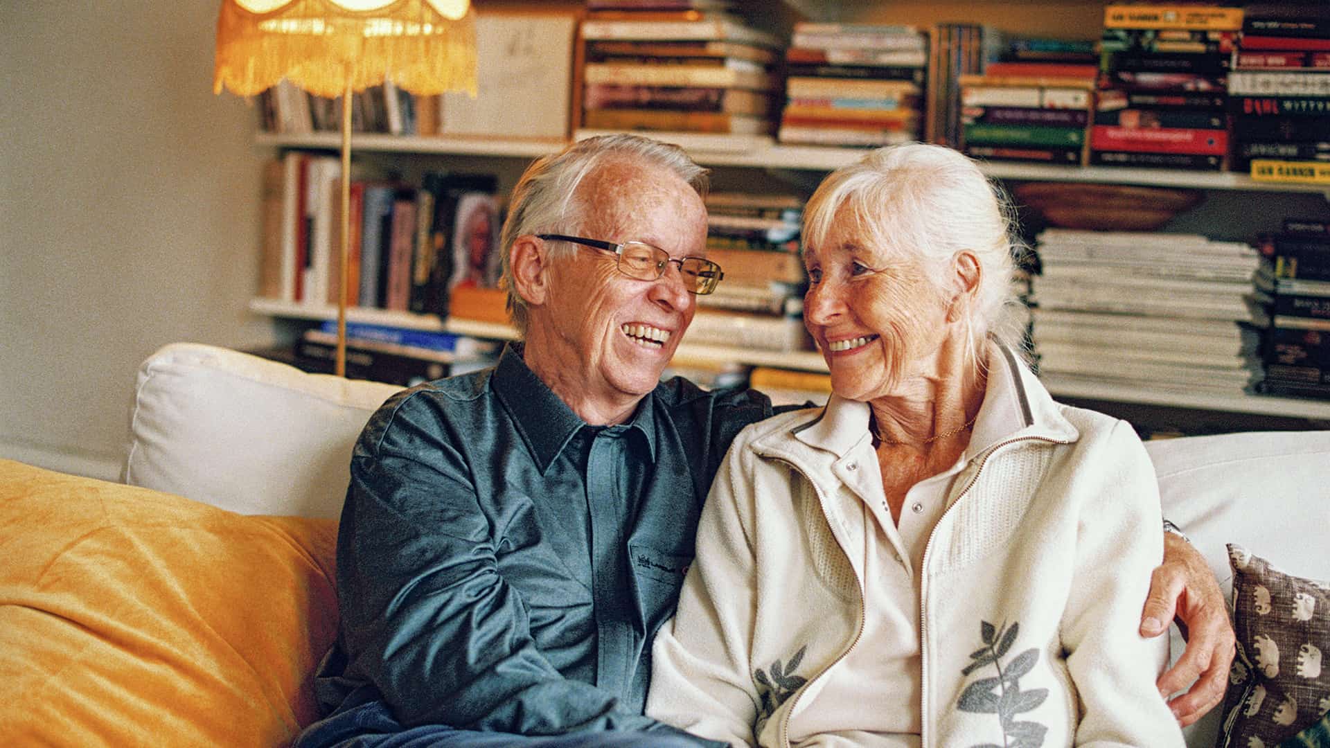 Ett äldre par sitter i en soffa och skrattar tillsammans.